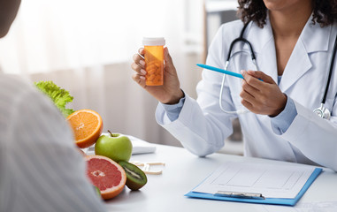 Obraz na płótnie Canvas Nutritionist showing slimming pills to female patient