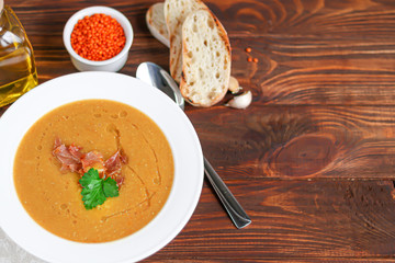 Vegetable soup with lentils on a wooden background. Served with chopped cherry tomatoes and herbs....