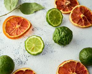 Combination of blood orange chips and fresh kaffir limes on a light colored background