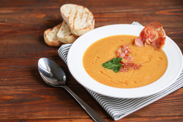 Vegetable soup with lentils on a wooden background. Served with chopped cherry tomatoes and herbs. Nearby are pieces of ciabatta. Raw groats in the background. Vegetarian dish.