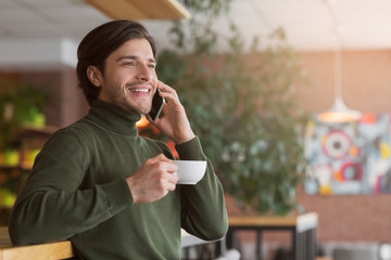 Successful young businessman drinking coffee and talking on phone