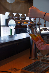 Pouring beer by young woman in polish pub 