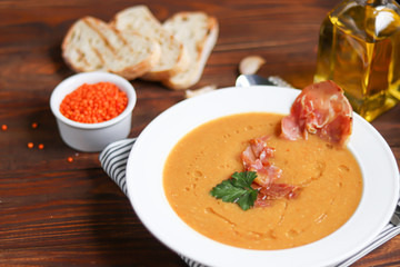 Vegetable soup with lentils on a wooden background. Served with chopped cherry tomatoes and herbs. Nearby are pieces of ciabatta. Raw groats in the background. Vegetarian dish.