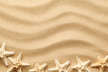 Fototapeta na wymiar Starfishes On Wavy Sand Background