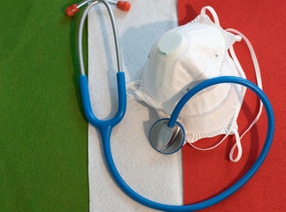 FFP2 face protection masks and a stethoscope over the background of the Italian flag in a concept...