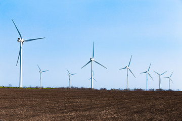 Wind turbines on blue sky background, Brown field