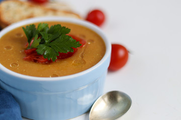 Vegetable soup with lentils on a wooden background. Served with chopped cherry tomatoes and herbs. Nearby are pieces of ciabatta. Raw groats in the background. Vegetarian dish.