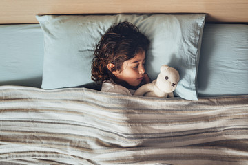 top view of a little girl sleeping with her toy