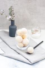 Homemade white chocolate, coconut and vanilla candy-truffles in the glass bowl on grey table
