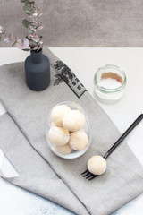 Homemade white chocolate, coconut and vanilla candy-truffles in the glass bowl on grey table