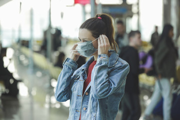 Woman wearing protective mask in airport, Coronavirus contagion fears concept