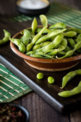 A close up of a rustic dish filled with edamame beans ready for eating.