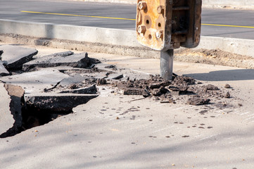 Male worker repairing driveway surface with jackhammer, digging and drilling concrete roads