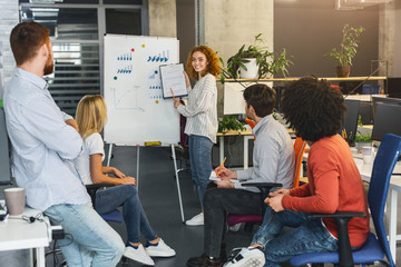Positive redhead girl making marketing presentation for colleagues