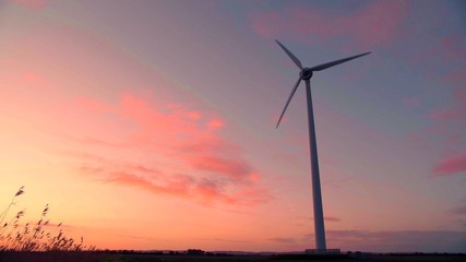 Fototapeta na wymiar Une éolienne pendant un coucher de soleil avec un ciel rose