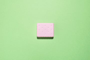 Minimal creative flat lay with decorative pink cracker at green pastel background.