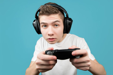 a schoolboy in headphones with a joystick from a game console in his hands