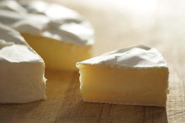 Camembert cheese slice and whole on a wooden table