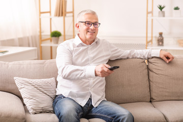 Elderly man watching tv sitting on sofa