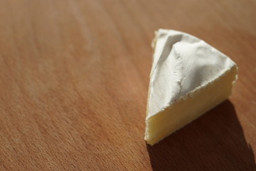 Camembert cheese slice on a wooden sunny table