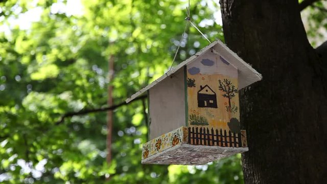birdhouse with decoration hanging on a tree in summer garden