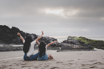 Madre e hija mirando el mar al atardecer feliz
