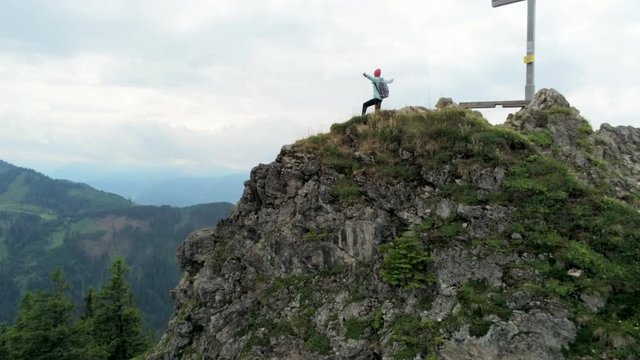 Aerial View of Woman Standing on Mountain Peak with Raised Arms Enjoying Successful Mount Reaching. Happy Female Hiker is on Top of Alps in Germany. Freedom Concept. 4K Pedestal Shot with Copy space