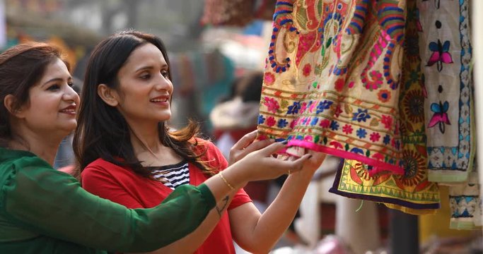 Two women shopping for dress at street market
