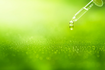 pipette mit vielen tropfen vor grünem frischen hintergrund, konzept für kosmetik oder pharmazie