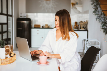 Happy beautiful woman in white shirt working on a laptop.