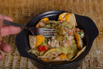 Casserole of Mexican nachos with guacamole and jalapeños