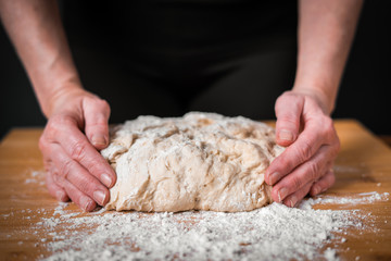 hands kneading dough on table