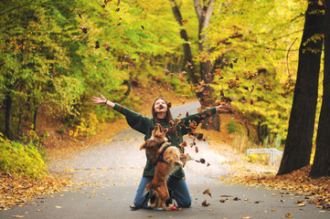Young woman and her dog (American Cocker Spaniel) sitting in the park and throws up leaves.
