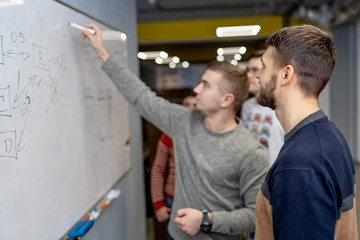 Professional crew of managers analyzing plan during meeting standing near flip chart,prosperous business partners looking at graphic of budget share ideas