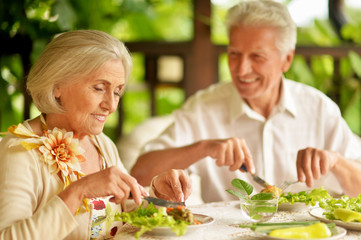 Portrait of happy senior couple having diner and posing on the veranda