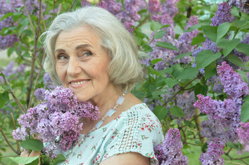 Close up portrait of happy senior beautiful woman with lilacs