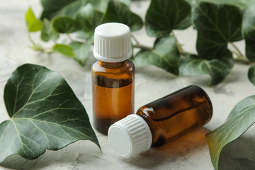 A leaf of ivy and syrup in a bottle on a light concrete table. Production of cough medicine with ivy extract. pharmaceutical industry