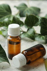 A leaf of ivy and syrup in a bottle on a light concrete table. Production of cough medicine with...