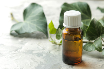 A leaf of ivy and syrup in a bottle on a light concrete table. Production of cough medicine with ivy extract. pharmaceutical industry
