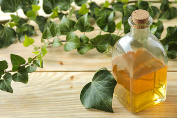 Ivy leaf and syrup in a bottle on a natural wooden table. Production of cough medicine with ivy extract. pharmaceutical industry