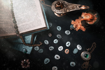 Astrology and esotericism. On a black background lie fortune-telling runes, a book, precious...