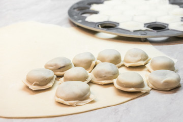 Fototapeta na wymiar Cooking homemade dumplings with ground beef close up. Rolled out dough and shape for simulation with filled cells. Flour products