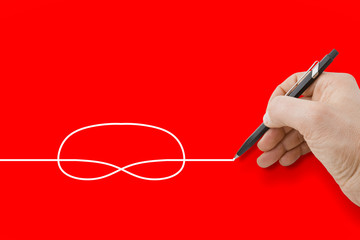 Hand holding a black pencil drawing a knot on red background