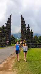 Obraz premium A couple standing in front of iconic Bali Handara Gate on a cloudy day. There are thick clouds around. The traditional Hindu gate to a gold course. Handara Gate is surrounded by lush green mountains