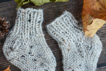 Chunky and warm hand-knitted baby socks on dark wooden background