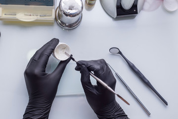 closeup, top view of the dentists hands, in gloves, holding a preparation preparation tool in his hand. Against the background of other dental instruments. Medical flatlay.