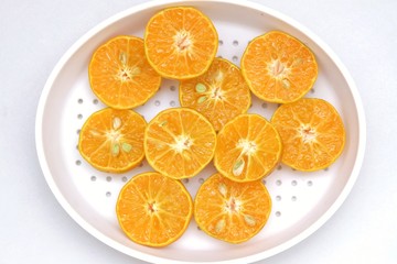 A group of half cut oranges fruit in a white bowl on white isolated background