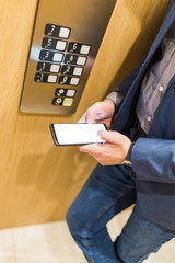 Unrecognizable businessman using mobile phone in elevator.