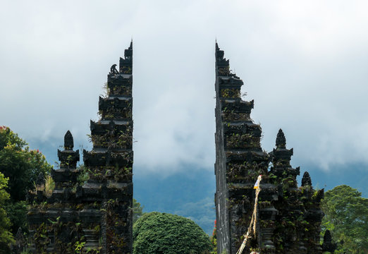 A close up on the front of iconic Bali Handara Gate on a cloudy day. There are thick clouds around. The traditional Hindu gate to a gold course. Handara Gate is surrounded by lush green mountains