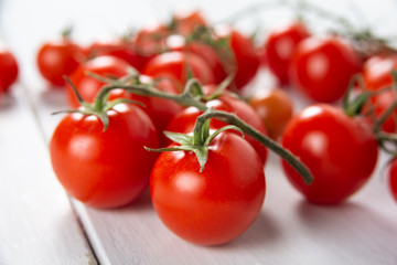Grappolo di pomodori ciliegini freschi su tavolo in legno bianco